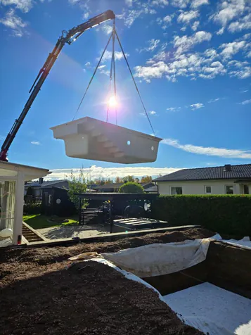 Glasfiberpool lyfts med kran över villaträdgård