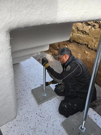 Montör justerar ställbara stödben under poolens trappa