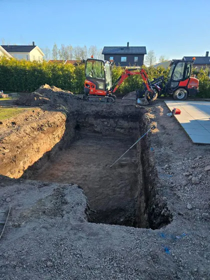 Minigrävare och nyschaktad poolgrop i villaträdgård