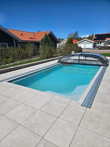 Pool med skenor för skjutbart pooltak och ljus plattsättning