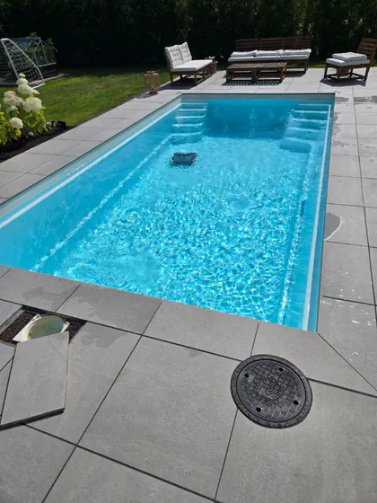 Glasfiberpool i drift med poolrobot och klart vatten