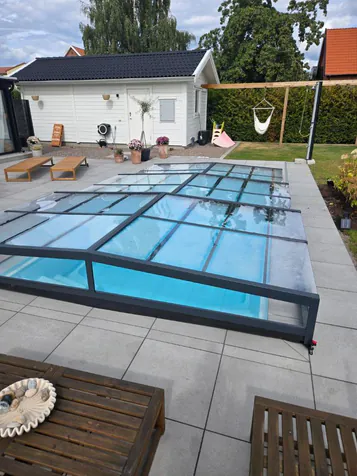 Lågt pooltak över pool med grå plattsättning