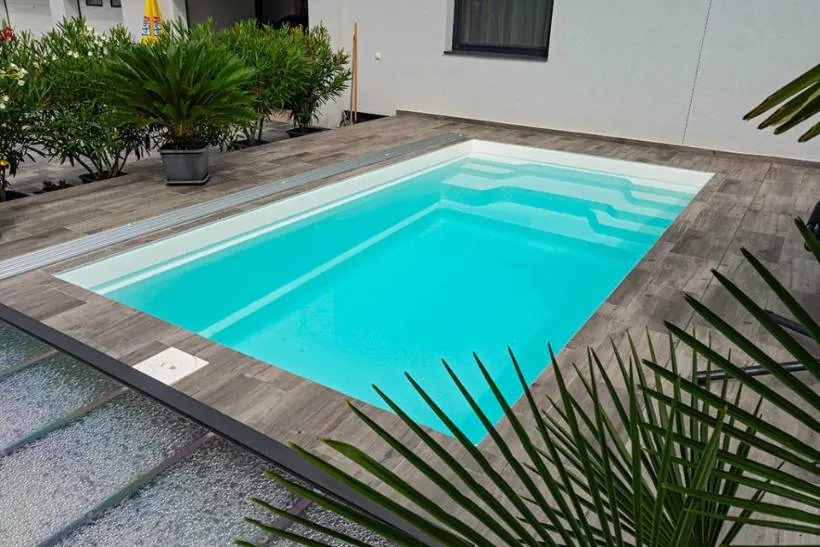 Färdig glasfiberpool med vatten i trädgårdsmiljö